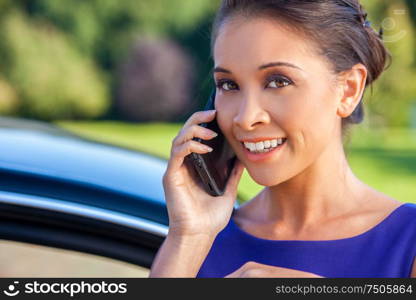 Beautiful happy Asian Eurasian Chinese biracial young woman or girl outdoor talking on cell phone by her car