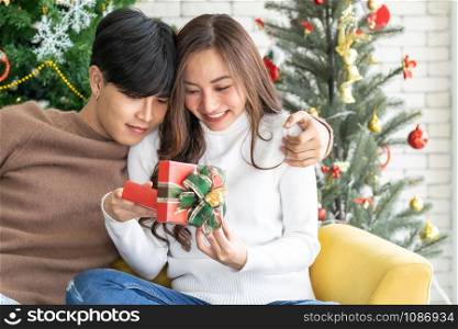 beautiful happy asian girl opening christmas present gift box from her boyfriend for Christmas holiday season greeting.
