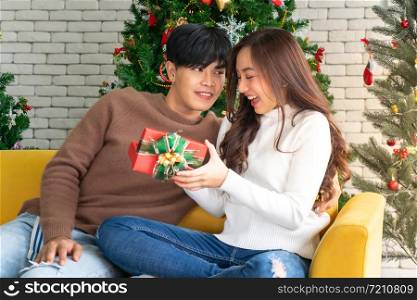 beautiful happy asian girl opening christmas present gift box from her boyfriend for Christmas holiday season greeting.