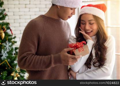 Beautiful happy asian girl receiving christmas present gift box from her boyfriend for Christmas holiday season greeting.