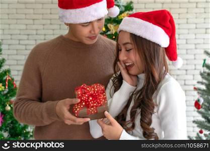 Beautiful happy asian girl receiving christmas present gift box from her boyfriend for Christmas holiday season greeting.