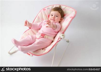 beautiful happy baby girl in a bouncer wearing pink onesie