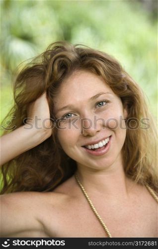 Beautiful happy Caucasian young adult woman in lush forest smiling and looking at viewer.
