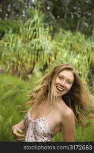 Beautiful happy Caucasian young adult woman in lush forest smiling and looking at viewer.