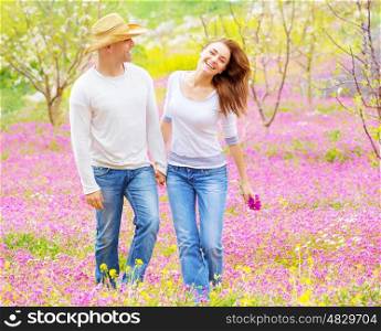 Beautiful happy couple enjoying spring nature, laughing and having fun outdoors, walking on purple floral glade, love concept