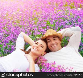 Beautiful happy couple lying down on purple lavender field, having fun on floral glade, summer nature, love concept
