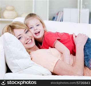 Beautiful happy family of young blond mother and her little pretty daughter - indoors