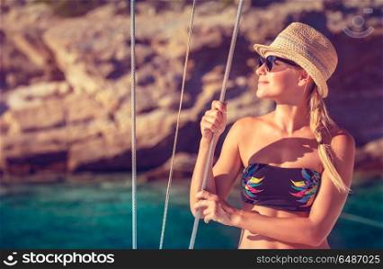 Beautiful happy girl tanning on the deck of sailboat, enjoying warm bright sun light, interesting adventure in the sea, beach summer vacation. Happy girl on summer vacation