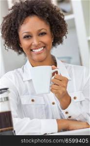 Beautiful happy mixed race African American girl or young woman with perfect teeth in her kitchen, drinking a mug of coffee