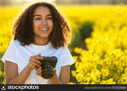 Beautiful happy mixed race African American girl teenager female young woman smiling outdoors in sunshine taking photographs with a camera