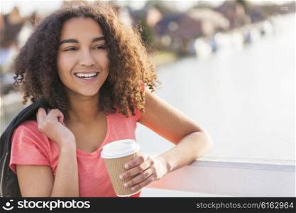 Beautiful happy mixed race African American girl teenager female young woman smiling drinking takeaway coffee outside on a bridge