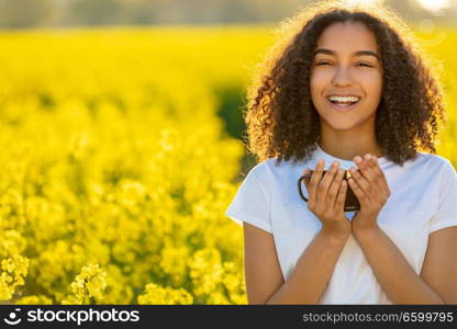 Beautiful happy mixed race African American girl teenager female young woman smiling drinking coffee or tea outdoors