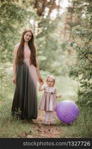 Beautiful happy mother with daughter having fun in green field holding balloons. mother and daughter with balloons. Mom, kid, mother.. mother and daughter with balloons. Beautiful happy mother with daughter having fun in green field holding balloons. Mom, kid, mother.