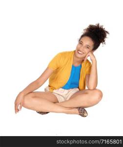 Beautiful happy multi-racial woman sitting on the floor in shorts and a yellow sweater with her curly black hair and smilingisolated for white background