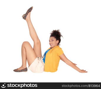 Beautiful happy multi-racial woman sitting on the floor lifting one leg up in shorts and a yellow sweater with her curly black hair and smiling isolated for white background