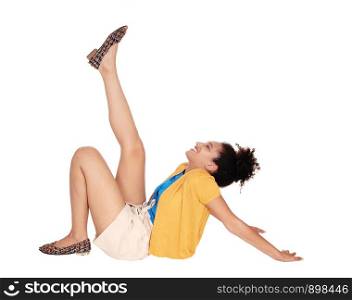Beautiful happy multi-racial woman sitting on the floor lifting one leg up in shorts and a yellow sweater with her curly black hair and smiling isolated for white background