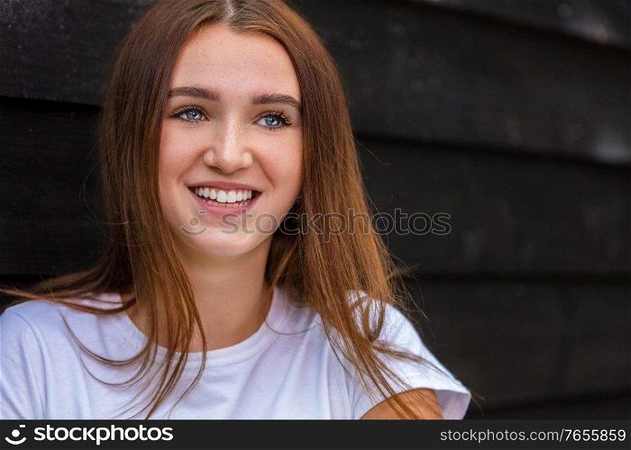 Beautiful happy smiling girl teenager female young woman with blue eyes and perfect teeth outside wearing a white t-shirt