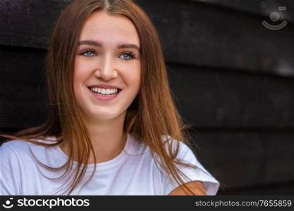 Beautiful happy smiling girl teenager female young woman with blue eyes and perfect teeth outside wearing a white t-shirt