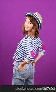 beautiful happy smiling teen girl in a hat posing on a purple background