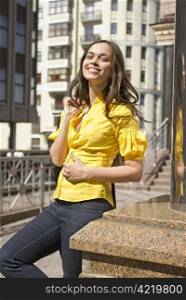 beautiful happy student in yellow blouse stands on the downtown