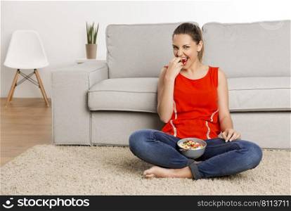 Beautiful happy woman at home eating a strawberries