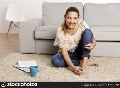 Beautiful happy woman at home making a pause to painting her nails