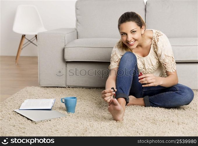 Beautiful happy woman at home making a pause to painting her nails