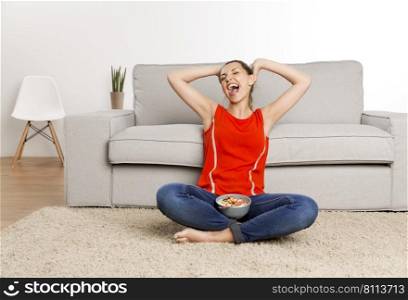 Beautiful happy woman at home sitting on the floor with a healthy bowl of food