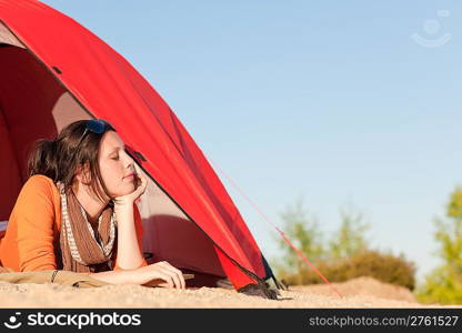 Beautiful happy woman camping lying and relaxing in tent