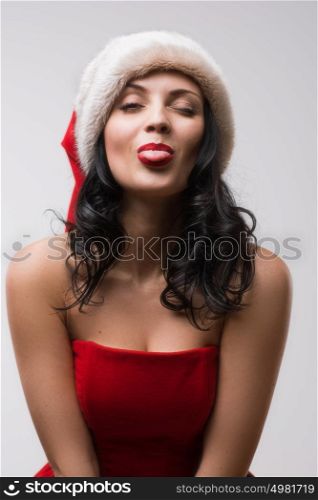 Beautiful happy woman in Santa Claus clothes pokes tongue