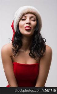 Beautiful happy woman in Santa Claus clothes pokes tongue