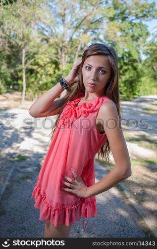 Beautiful happy woman in spring park in pink dress with bright makeup and hairstyle relaxing. Alluring girl resting at summer nature. retro portrait of sexy brunet smiling outdoor posing at sunny day