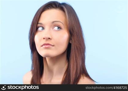 beautiful happy woman is looking sideways and touching her face on blue background