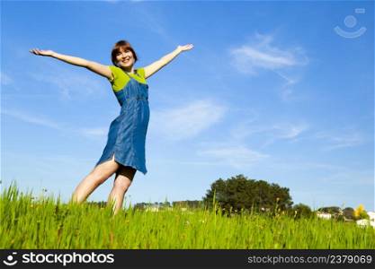 Beautiful happy woman on a green meadow with arms open