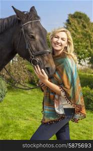 Beautiful happy woman wearing poncho, smiling and leading her horse in sunshine