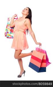 Beautiful happy woman with shopping bags on shoppingspree standing cute with leg looking up, consumer lifestyle concept.
