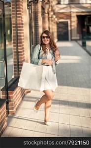 Beautiful happy woman with white paper bag at shopping mall