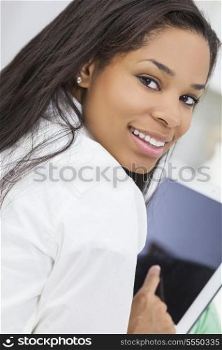 Beautiful happy young African American woman or girl smiling and using a tablet computer