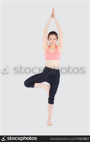 Beautiful happy young asian woman doing yoga exercise sport for leisure and relax isolated on white background, asia girl standing workout with stretch muscle arm for healthy and wellbeing.