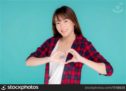 Beautiful happy young asian woman wear travel summer gesture heart shape with hand having confident isolated on blue background, asia teenager girl expression with cheerful and fun while trip.