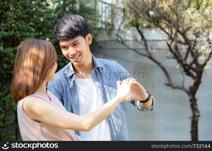 Beautiful happy young couple fun making gesture heart shape with hand outdoor together, man and woman with relation feeling love with symbol and sign in the garden, lover and romantic concept.