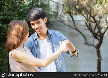 Beautiful happy young couple fun making gesture heart shape with hand outdoor together, man and woman with relation feeling love with symbol and sign in the garden, lover and romantic concept.