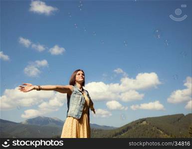 Beautiful happy young girl playing with soap bubbles