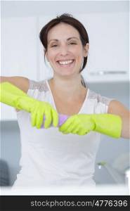 beautiful happy young housewife wearing gloves and holding a detergent