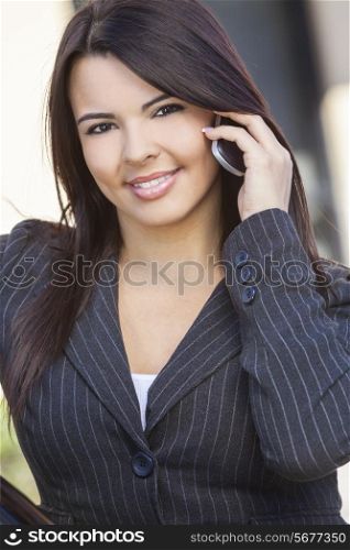 Beautiful happy young Latina Hispanic woman or businesswoman smiling and talking on her cell phone outside