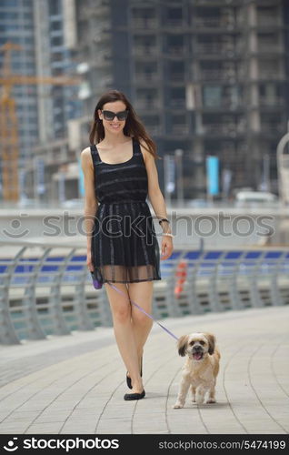 beautiful happy young woman in black dress with cute small dog puppy have fun on street