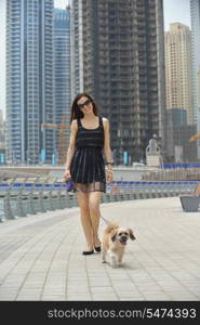 beautiful happy young woman in black dress with cute small dog puppy have fun on street