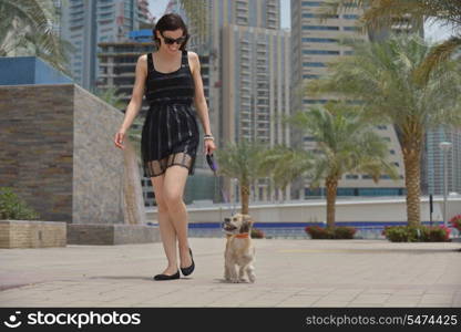 beautiful happy young woman in black dress with cute small dog puppy have fun on street