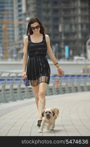 beautiful happy young woman in black dress with cute small dog puppy have fun on street