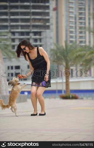 beautiful happy young woman in black dress with cute small dog puppy have fun on street